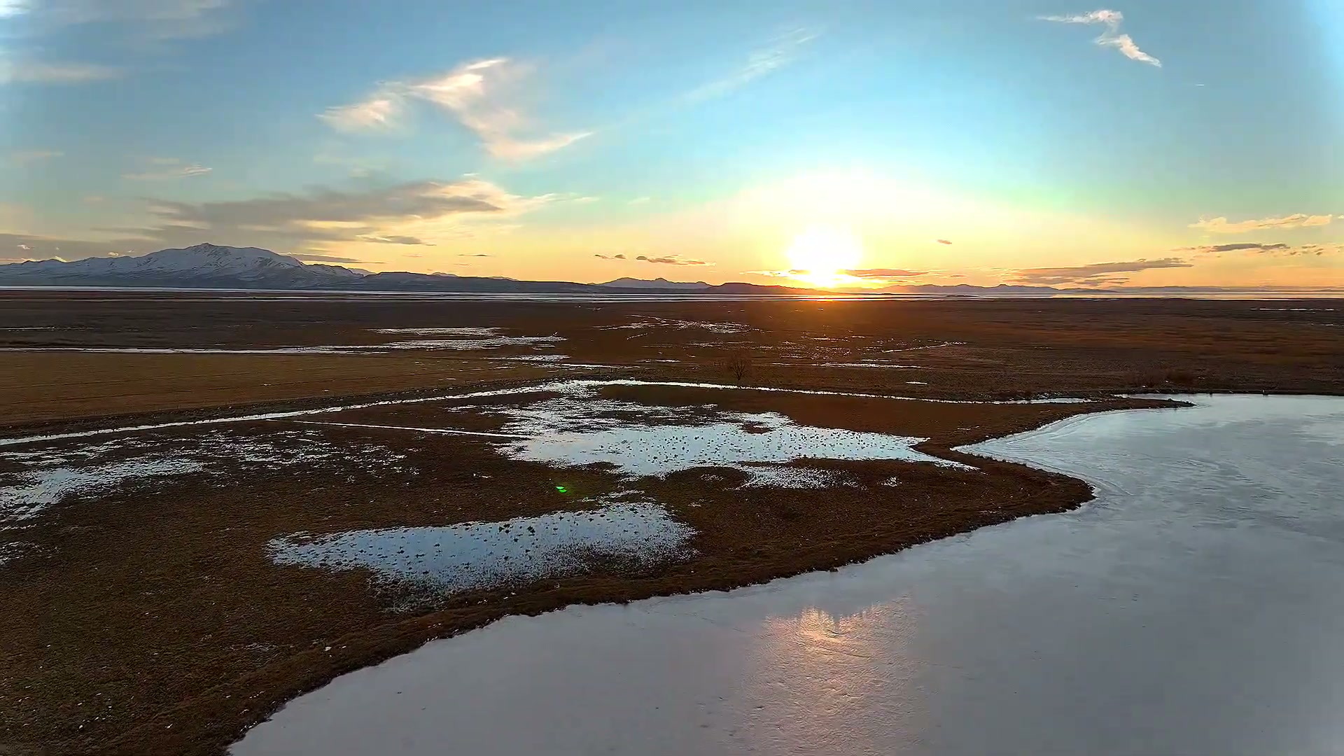 The sun setting over marsh water and a winding shoreline
